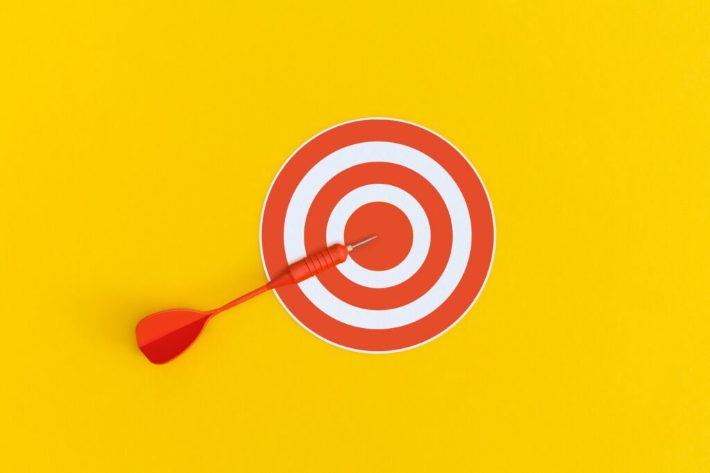 Dart on red target on a yellow background. Top view. Flat lay.